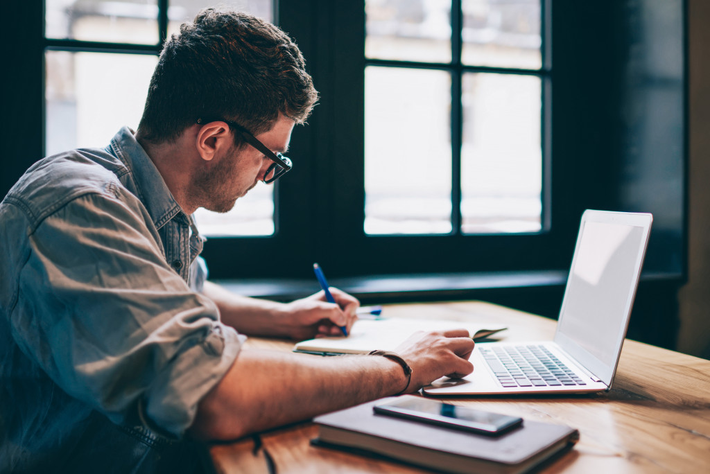 Man working with his laptop and notebook