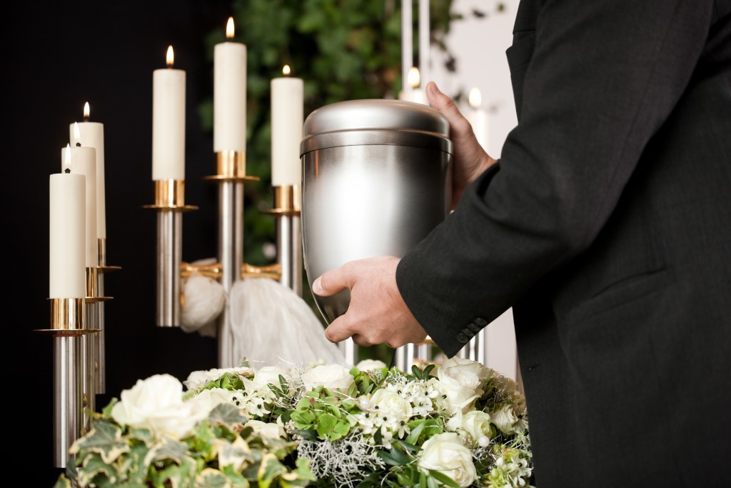 Funeral concept with urn, white roses, and candles