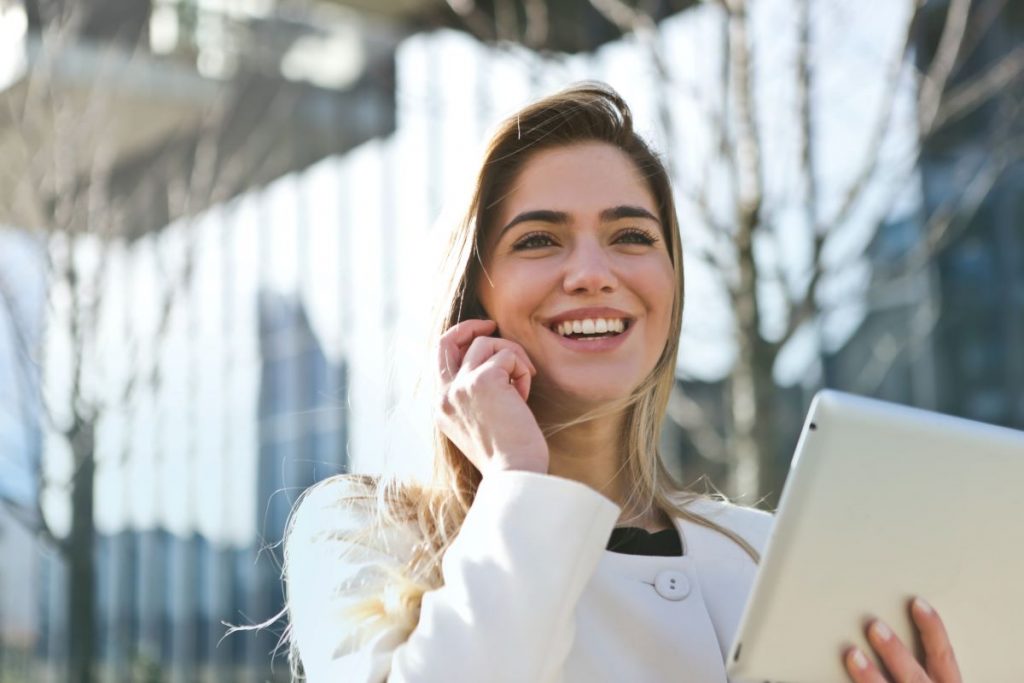 woman smiling while holding tablet